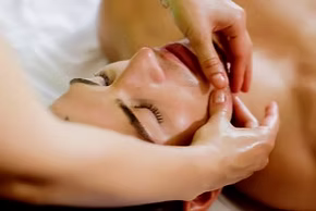 Therapist performing TMJ massage focusing on the jaw and neck area